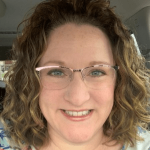 Charlotte Chalakee, a white woman with curly brown hair and glasses.
