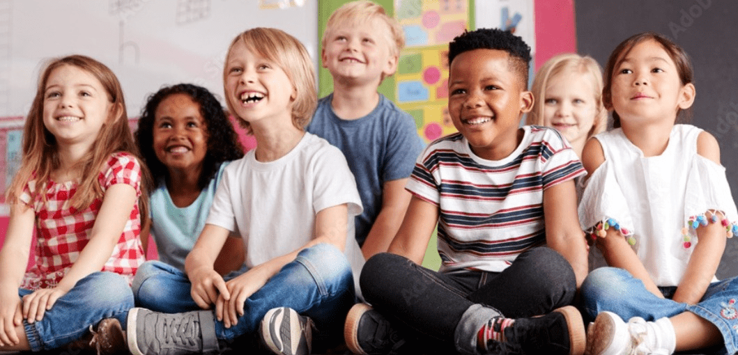 Group of children sitting and smiling in a classroom.