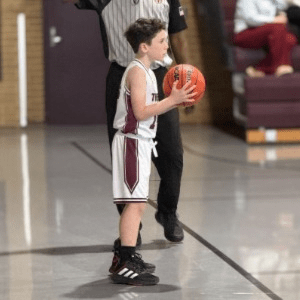 Boy holding a basketball staring down court.