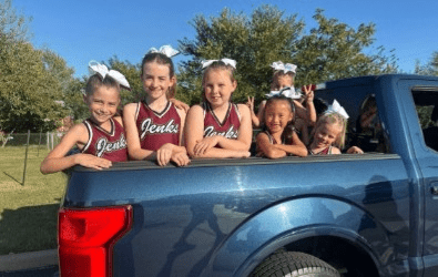 Pom and Cheer students riding in truck for parade.