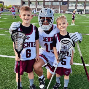 two youth lacrosse players with older player